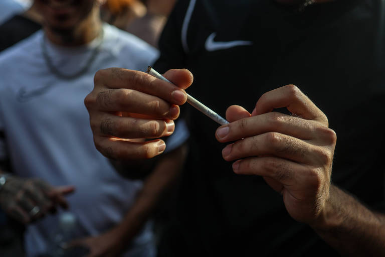 Homem segura um cigarro de maconha com as duas mãos durante a Marcha da Maconha em São Paulo