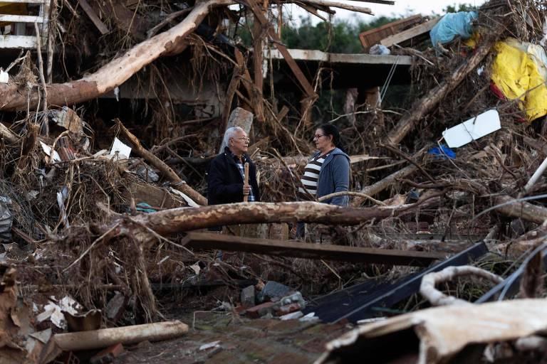 Mulheres observam série de destroços em imóveis atingidos pelas enchentes no Rio Grande do Sul