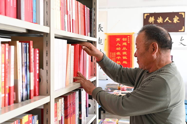 Homem arruma livros em estante de biblioteca na província de Gansu, na China
