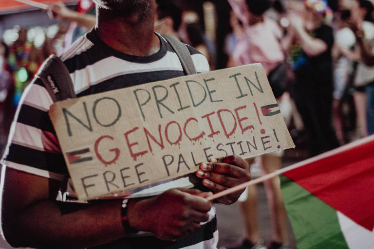 Manifestante segura pedaço de papelão com frase 'No pride in genocide" ('Sem orgulho no genocídio', em português) nos EUA