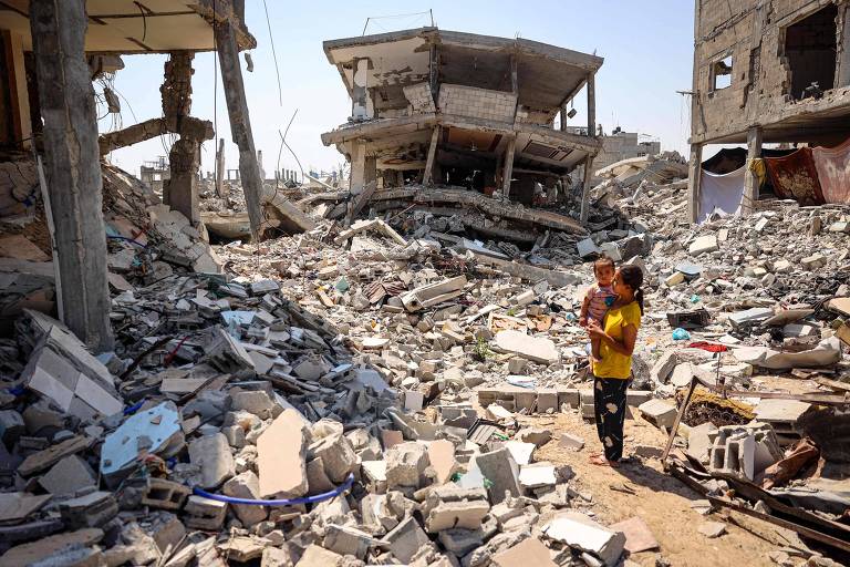 Palestinos em região destruída de Khan Yunis, no sul da Faixa de Gaza,