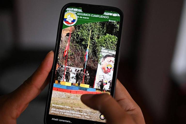 Imagem de uma mão segurando um telefone celular mostrando uma conta de TikTok que promove um dos grupos armados dissidentes da Colômbia