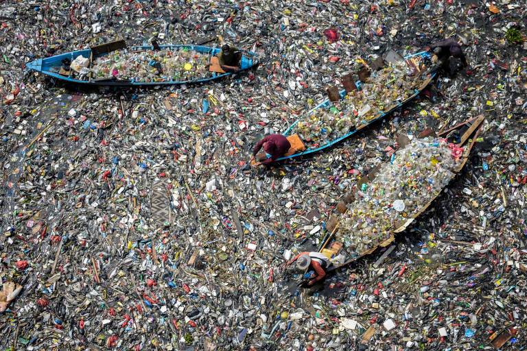 Barcos coletam resíduos plásticos que tomaram o rio Citarum na cidade de Bardung, em Java, na Indonésia