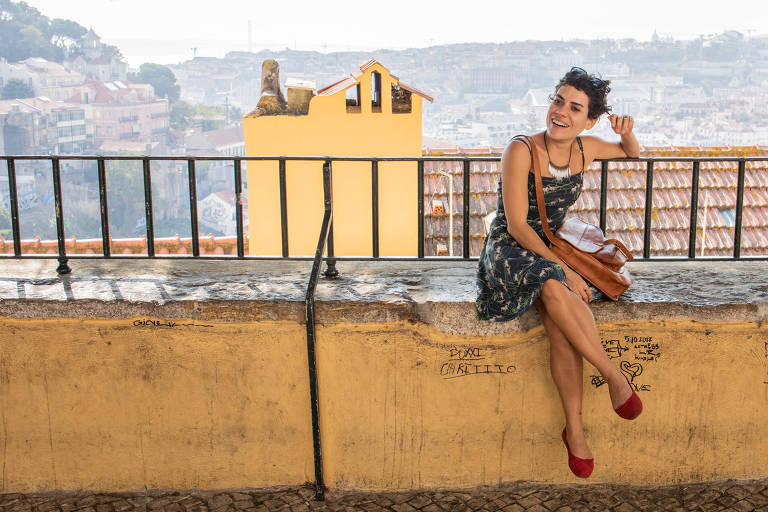 A poeta Adelaide Ivánova sentada num banco de concreto com uma paisagem ao fundo