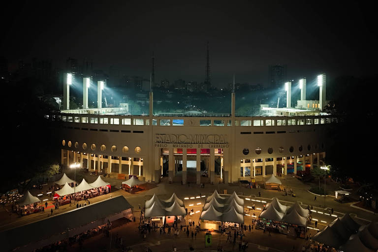 estádio e tendas brancas iluminados por holofotes