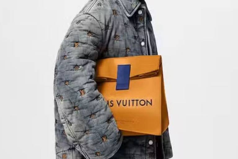 Homem segura uma bolsa amarela que se assemelha a um saco de pão e onde se lê "Louis Vuitton"