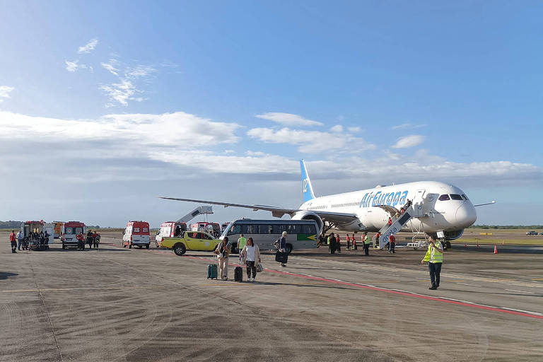 foto mostra avião sem avarias em pista de aeroporto com profissionais em torno dele. ao fundo, ambulâncias. faz sol e o céu está azul, com poucas nuvens
