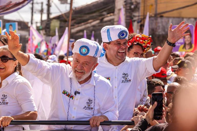 Lula e Geraldo Júnior usam camisa branca, turbantes do afoxé Filhos de Gandhy e acenam