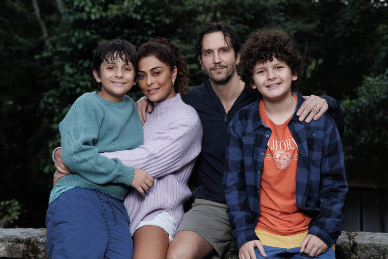 A imagem mostra uma família de quatro pessoas posando para uma foto ao ar livre