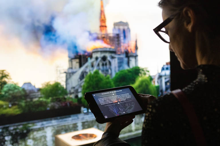 Mulher usa tablet interativo na exposição 'Notre-Dame de Paris: uma viagem pela Catedral'