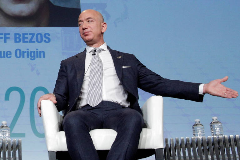 Jeff Bezos veste terno e gravata e gesticula durante entrevista coletiva