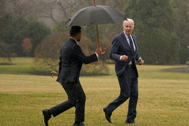 Sob chuva forte, Joe Biden pega um guarda-chuva ao chegar de volta à Casa Branca após fazer um exame médico de rotina em Washington, em fevereiro de 2023