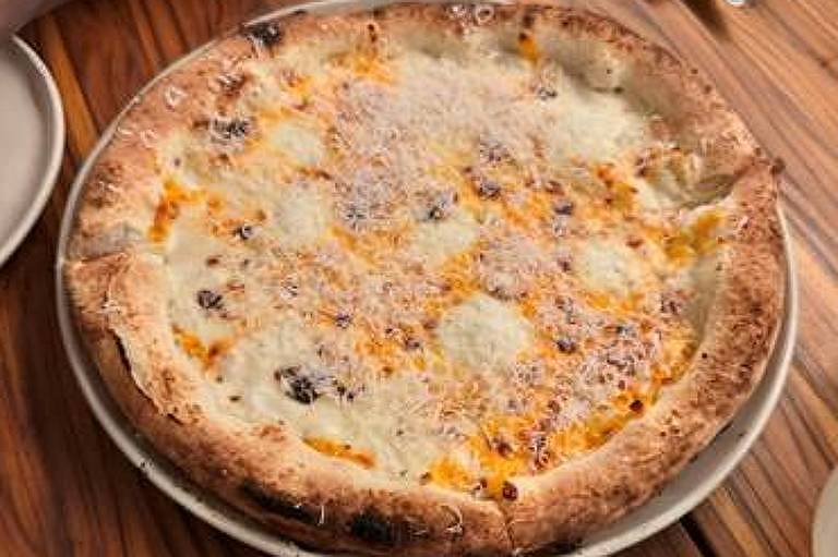 Uma pizza de queijo sobre uma mesa de madeira. A pizza tem uma crosta dourada e está coberta com uma camada generosa de queijo derretido e ralado. Há pratos e talheres ao redor da pizza.