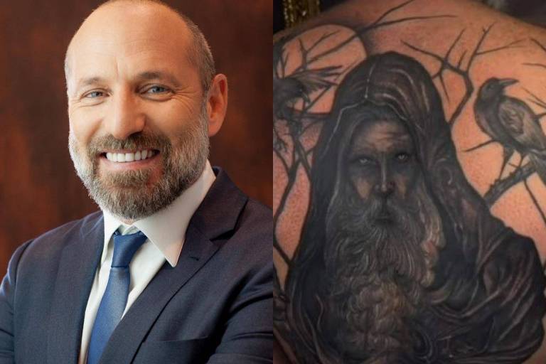 Homem de barba e terno ao lado de tatuagem