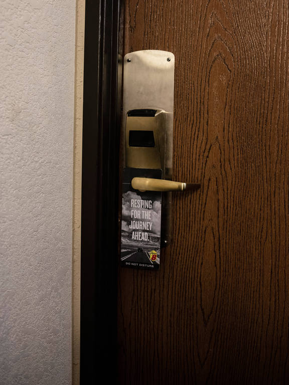 Imagem de uma maçaneta de porta de madeira com um aviso pendurado.