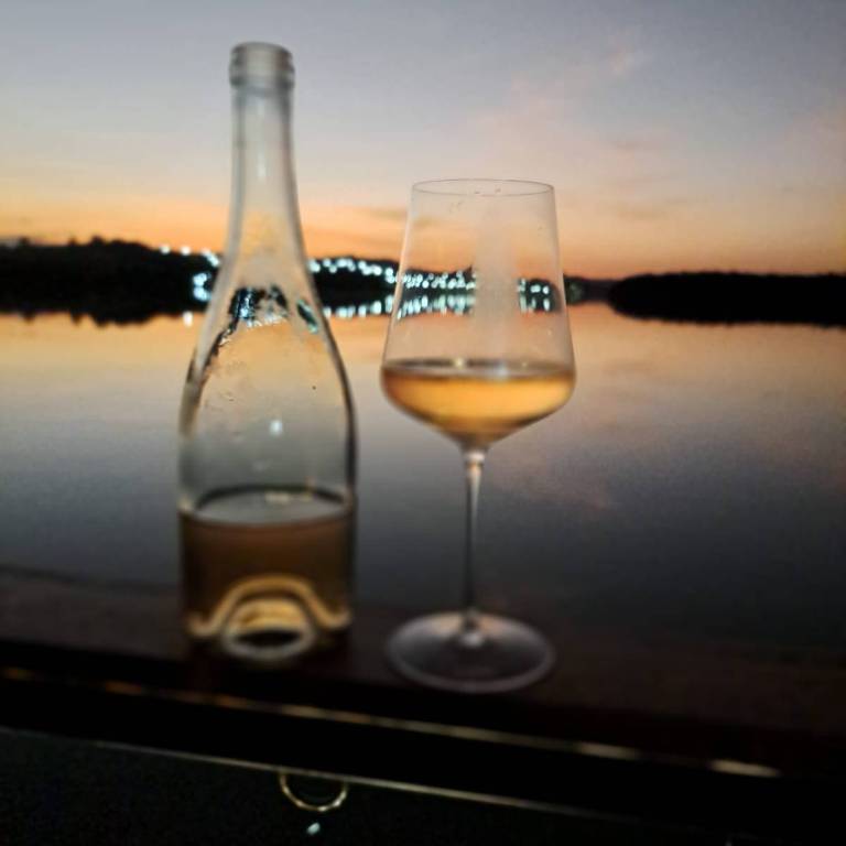 garrafa e taça de vinho com por do sol ao fundo