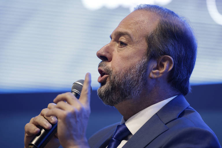 Imagem de Alexandre Silveira, ministro de Minas e Energia, que é um homem debarba e cabelo curto, e está vestindo um terno azul com gravata. O fundo é desfocado, com tons de azul e branco.