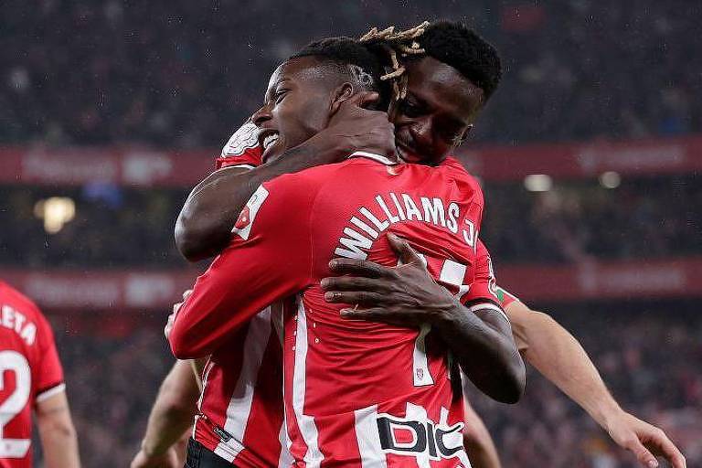 Nico e Iñaki Williams se abraçam em campo com camisa vermelha do  Athletic Club de Bilbao