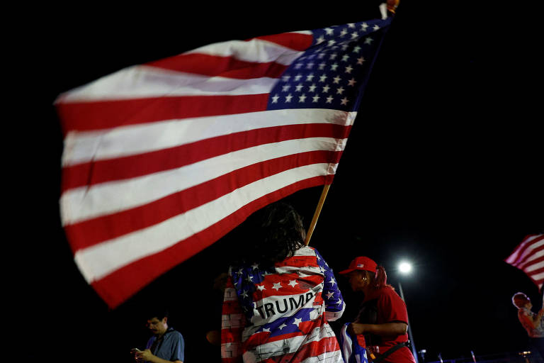 Uma pessoa balança uma bandeira americana após o candidato republicano Donald Trump ficou ferido por tiros disparados durante comício