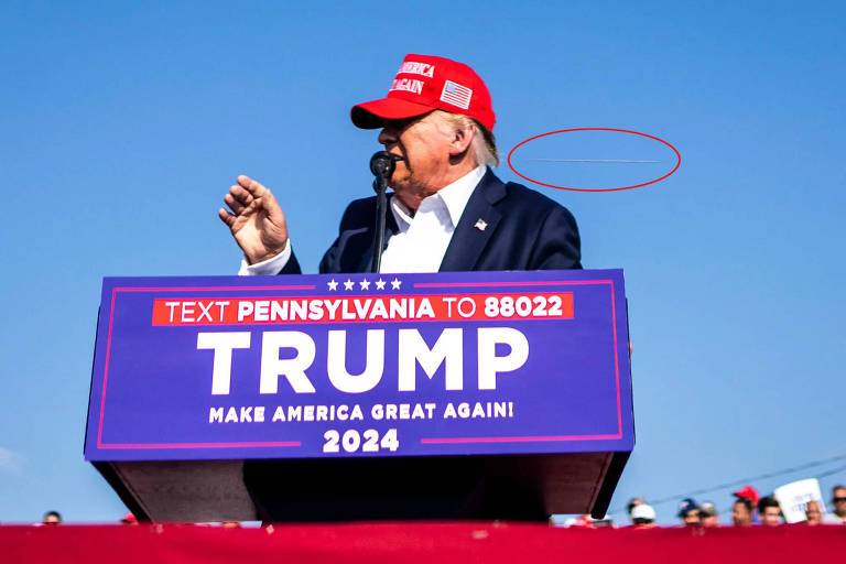 Imagem do ex-presidente Donald Trump no comício em que ele foi alvo de um atentado a tiros. A imagem mostra o que parece ser uma bala no ar próxima à cabeça de Trump.