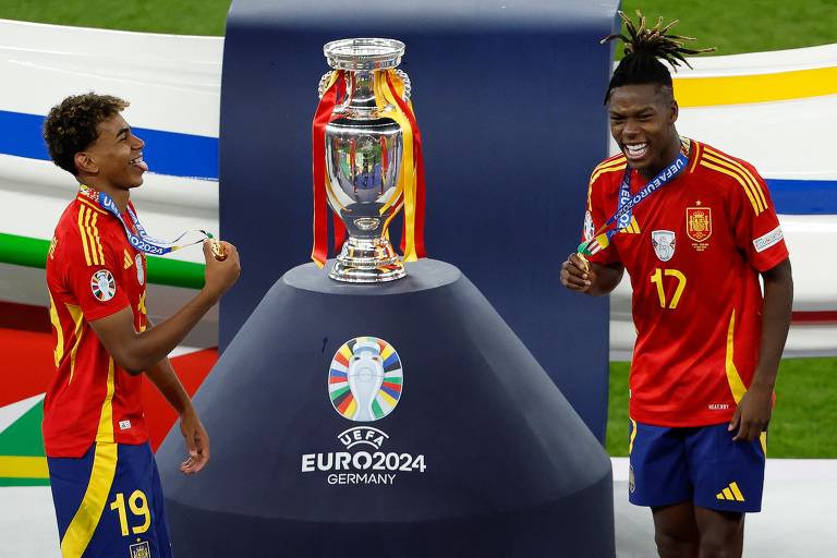 Lamine Yamal e Nico Williams comemoram ao lado do troféu depois de vencer a final da UEFA Euro 2024 entre Espanha e Inglaterra