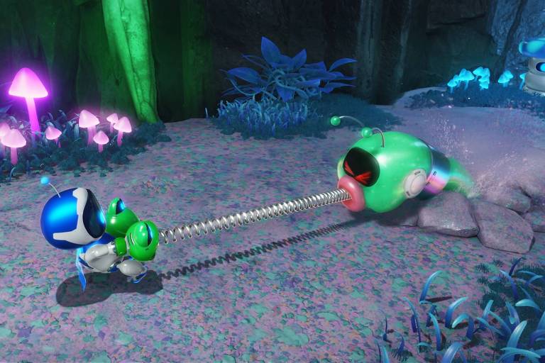 A imagem mostra uma cena de um jogo de vídeo com dois personagens robóticos em um ambiente subterrâneo. O personagem à esquerda, com um capacete azul, está puxando uma criatura verde com uma língua extensível. O cenário ao redor é iluminado por cogumelos brilhantes e plantas bioluminescentes, criando uma atmosfera de caverna alienígena.