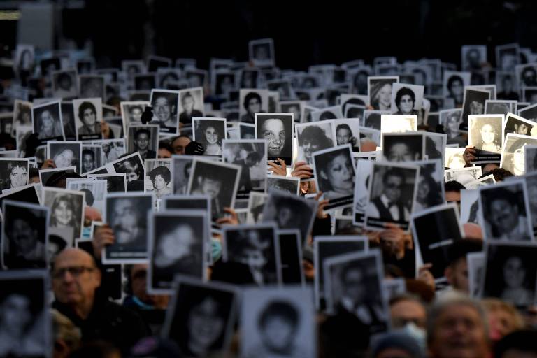Parentes de vítimas do atentado contra a Amia seguram fotos de seus failiares no aniversário de 28 anos do ataque, em 2022, em Buenos Aires