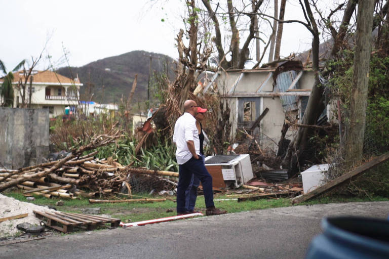 Homens em uma rua com casas destruídas