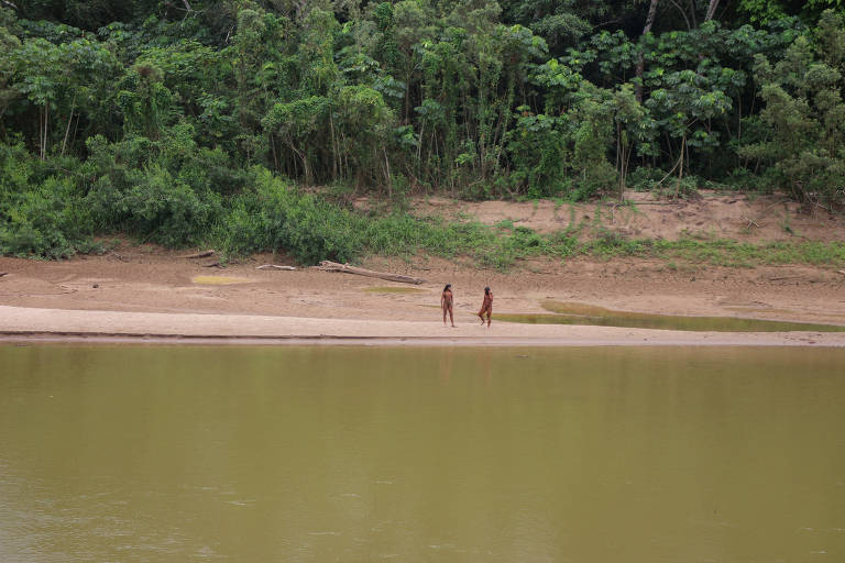 Dois indígenas na margem de um rio