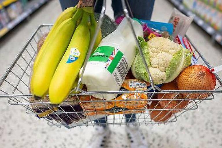 Cesta com compras de supermercado, como um cacho de bananas, leite, brócolis, cebola