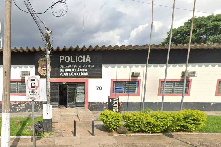 Imagem da fachada da Delegacia de Polícia de Hortolândia. O prédio é branco com detalhes em preto e vermelho, possui várias janelas com grades e ar-condicionado