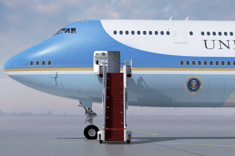 Foto mostra a parte da frente de um avião grande, com dois andares, pintado de azul e branco. Uma porta está aberta e uma escada, colocada