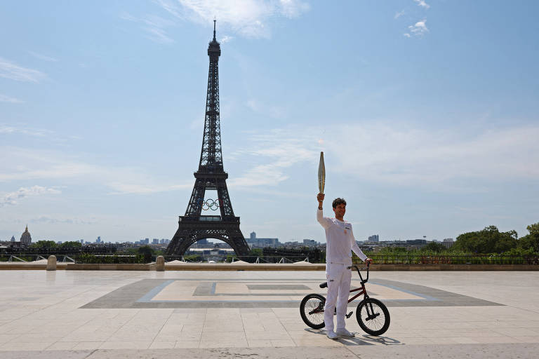 O ciclista francês de BMX, Matthias Dandois, posa com a tocha olímpica em frente à Torre Eiffel
