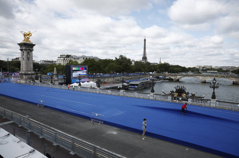 Voluntários preparam a pista de triatlo na ponte Alexandre III