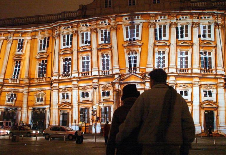 Pessoas observam a projeção de imagens na fachada do museu de Belas Artes em Lyon, na França