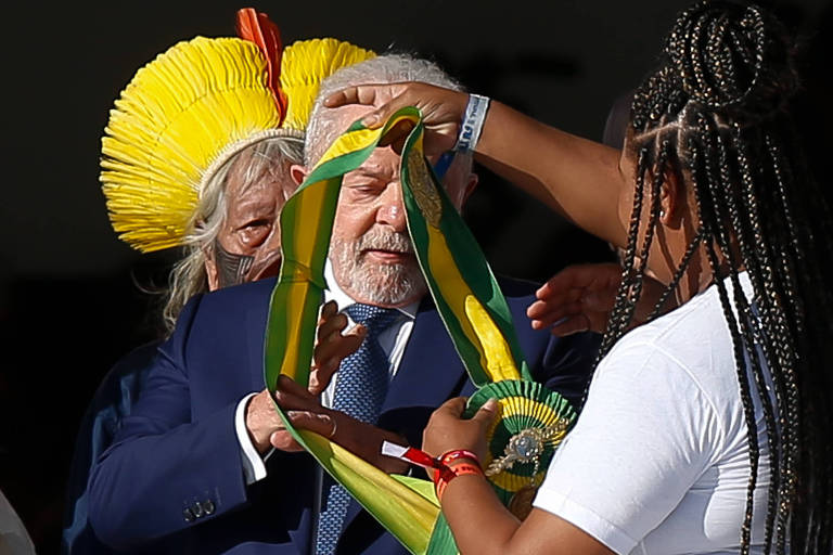 O presidente Luiz Inácio Lula da Silva recebe a faixa presidencial da catadora Aline Souza durante a cerimônia de posse no Palácio do Planalto