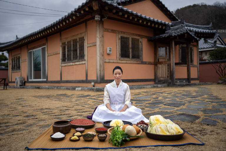 Mulher coreana sentada em frente a uma casa marrom