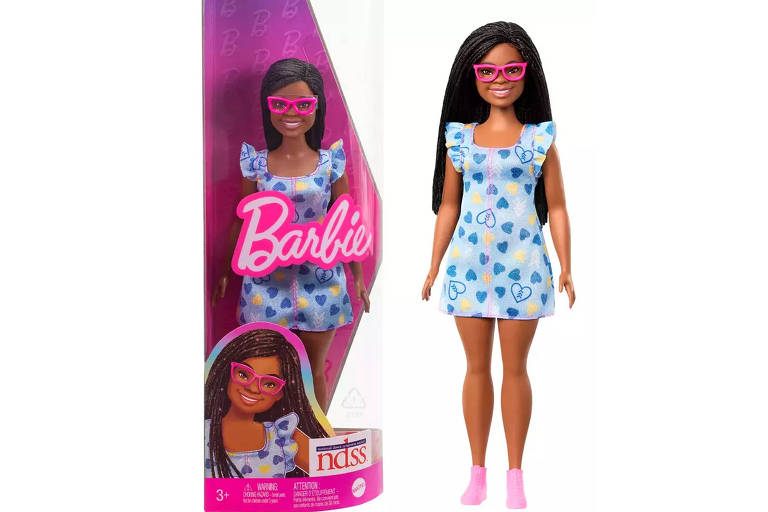Boneca negra e de óculos com aro rosa, vestido florido de azul. À esquerda, aparece a caixa escrito "Barbie"