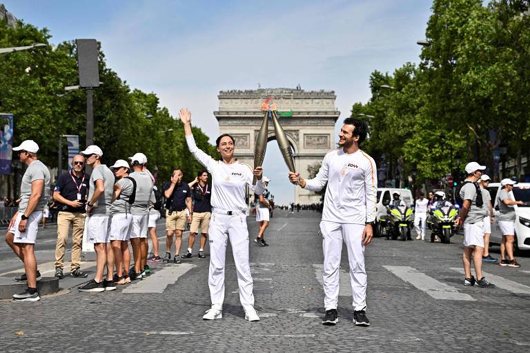 Chef francesa Nina Metayer e cantor franco-israelense Amir seguram a tocha olímpica na avenida Champs-Elysees, em Paris