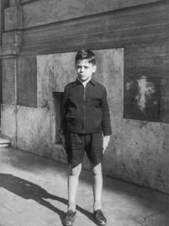 menino de cabelo penteado, sapatos, blusa de manga comprida e bermuda curta em foto em preto e branco