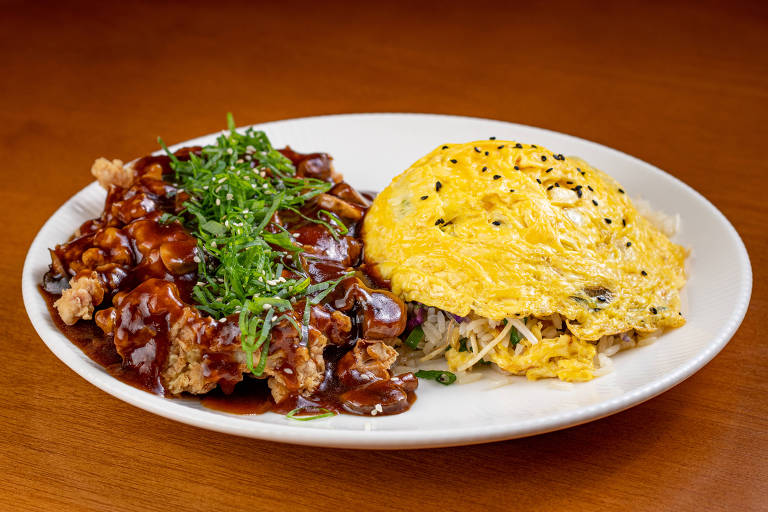 Um prato com frango empanado coberto por um molho escuro e cebolinhas picadas, ao lado de uma omelete amarela com sementes pretas, servidos sobre uma cama de arroz com vegetais.