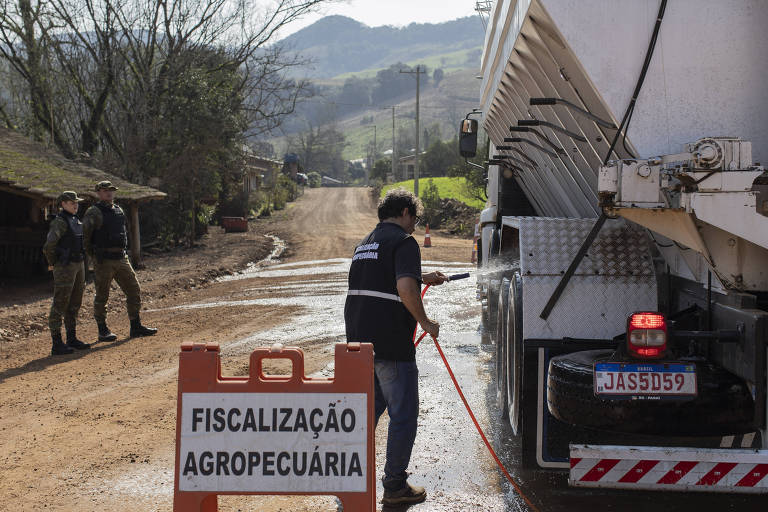 Fiscal agropecuário e policiais militares fazem barreira sanitária para higienizar veículos no interior de Anta Gorda (RS), após foco da doença de Newcastle no município