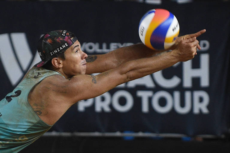 Usando boné e camiseta verde claro, o jogador Arthur Lanci executa uma manchete em jogo de vôlei de praia em Brasília 