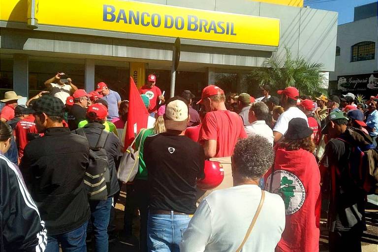 grupo de pessoas protesta em frente a banco