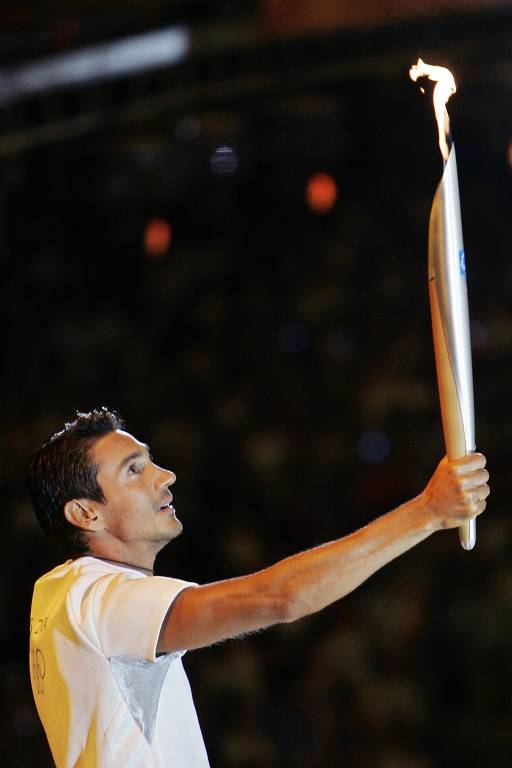 Medalhista olímpico, Nikolaos Kaklamanakis, da vela, com a tocha olímpica nas Olimpíadas de Atenas, em 2004