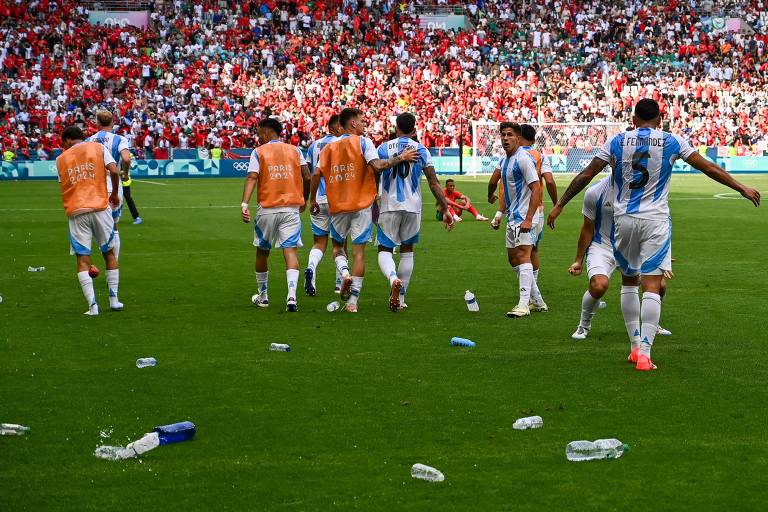 Em Saint-Étienne, jogadores da Argentina caminham perto de garrafas de plástico arremessadas contra eles por torcedores no jogo contra Marrocos