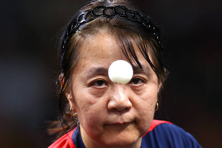 A mesa-tenista Tania Zeng, do Chile, que tem 58 anos, observa a bolinha na partida nas Olimpíadas de Paris contra a libanesa Mariana Sahakian