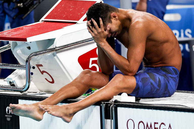 A foto mostra o nadador brasileiro Guilherme Costa "Cachorrão" churando sentado na bordfa da piscina após chegar em quinto lugar na final dos 400m livres. Parisd-2024