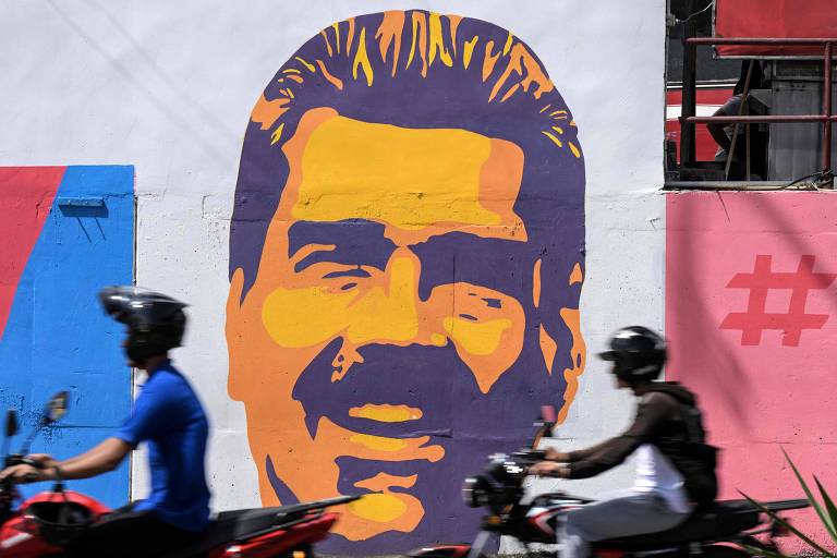 Motocicletas perto de grafite com o rosto de Nicolás Maduro, na capital Caracas