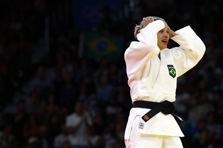 Usando quimono branco, a judoca brasileira Larissa Pimenta, emocionada, leva as mãos à cabeça depois de conquistar o bronze na categoria até 52 quilos nas Olimpíadas de Paris